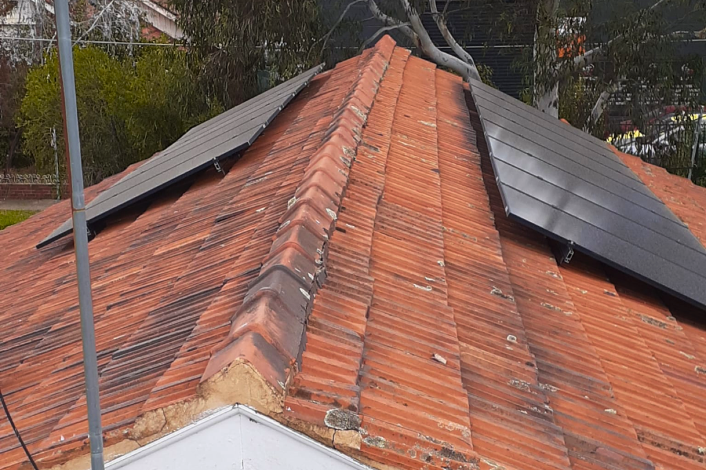 A terracotta tile roof with solar panels on each side.